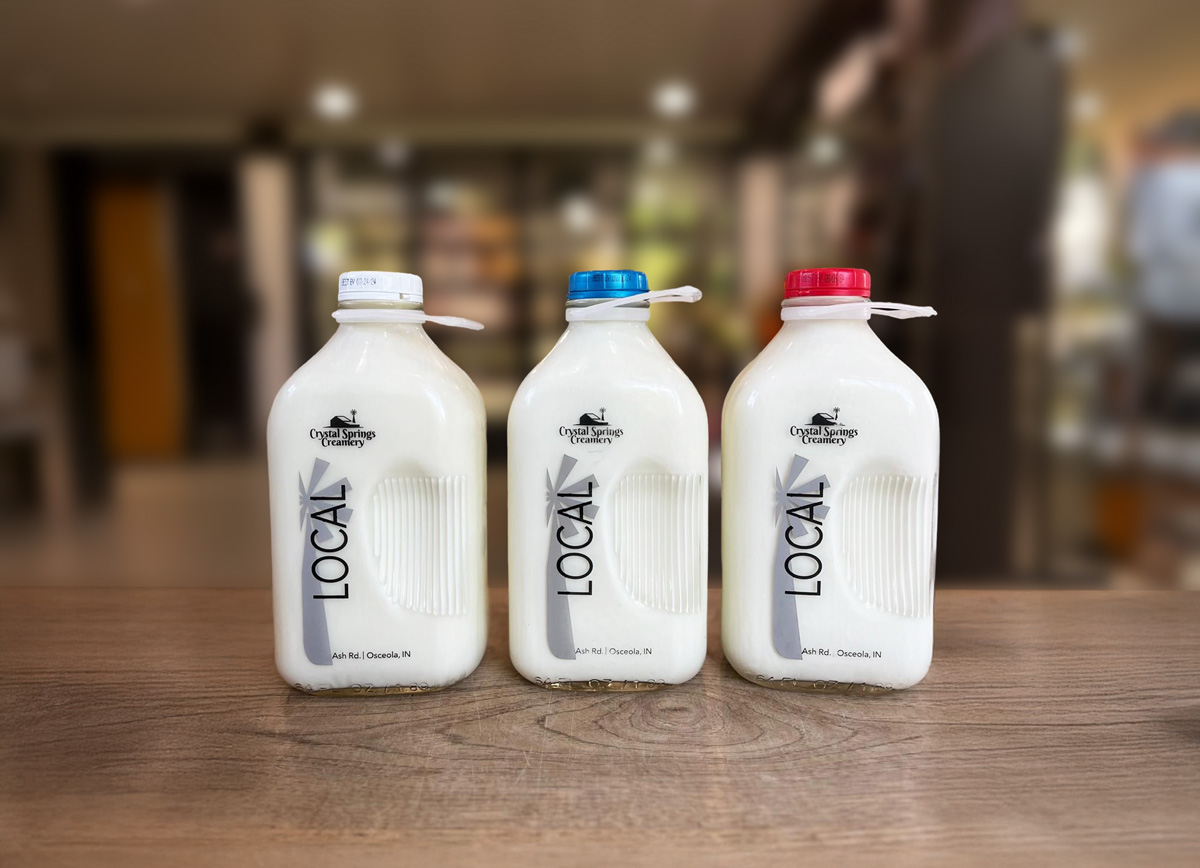 A row of Crystal Springs milk bottles sitting on a store counter